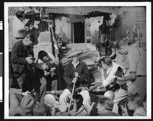 Group of news photographers snapping pictures of a Chinese man dressed as a coolie, ca.1940