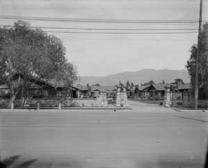 Exterior view of a California bungalow court with the San Gabriel Mountains in the background, Pasadena, ca.1916