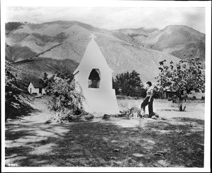 Woman standing near the Pauma Indian Mission Campanario or bell tower, ca.1900