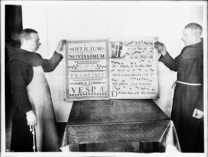 Monks displaying an illuminated score at Mission Santa Barbara, California, ca.1904