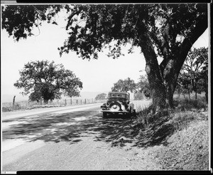 An early-model automobile parked on the shoulder of a two-lane concrete road in the country, Ventura County, 1930