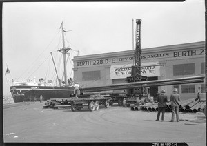 Dock scene at Los Angeles Harbor, showing steel pipes being loaded on a truck, September 17, 1930