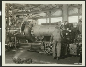 Interior of an unidentified factory where a worker is "machining heat exchanger bodies", ca.1930