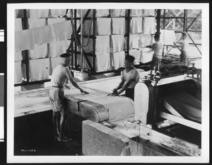 Workers passing slabs through a series of metal cylinders at the Goodyear Tire and Rubber Company, ca.1930