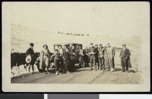 People standing on a dirt road in front of an automobile, ca.1925