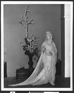 Woman in costume posing near a banzai tree, ca.1930