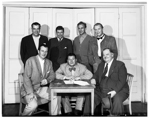 John Wayne and Oliver Hardy posing with a group of men