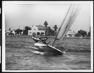 Man and woman working the lines of their sailboat on the ocean, ca.1930