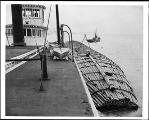 Large raft of lashed logs attached to the side of a boat traversing the Columbia River, ca.1925