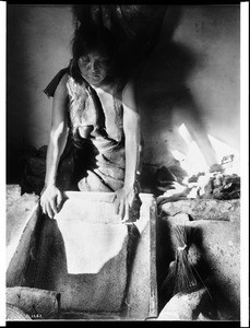 Young Hopi Indian woman grinding corn for flour, ca.1900