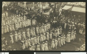 Postcard from the Los Angeles Preparedness Parade showing women in white marching with flags, June 14, 1916