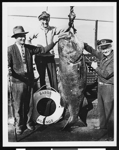 Three men posing with their catch, ca.1930