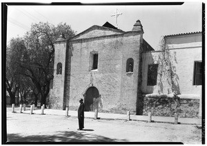 A priest in front of a church at the San Gabriel Mission