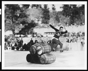 An ice skater performing jumps over barrels at Big Pines mountain camp, ca.1930