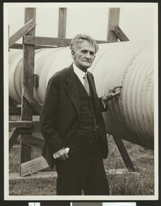 Dr. Albert Abraham Michelson, the first American to receive the Nobel Prize in sciences, standing next to the vacuum tube he used to measure the velocity of light, ca.1930