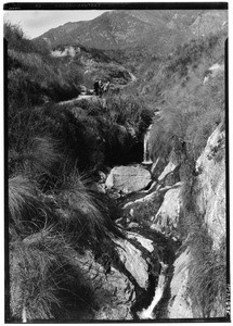 Hikers near a curving mountain stream