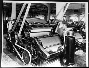 Man working with what appears to be a drying machine in an unidentified textile mill