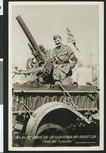 Smiling Pat O' Brian atop a captured German anti-aircraft gun at the World War I Allied War Exposition in Los Angeles, August 1-10, 1918