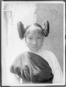 Young Hopi Indian girl with hair worn up in large buns at the side of her head, ca.1900