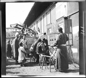 Men at a streetside peepshow in China, ca.1900