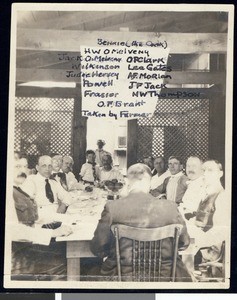 A group of fishing club members at a dinner table, perhaps members of the Sunset Club, ca.1910-1920