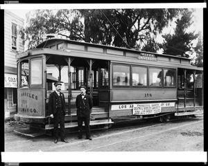 External view of a Plaza University trolley car of the Los Angeles Railway Company, showing two conductors posed in front, ca.1900-1910