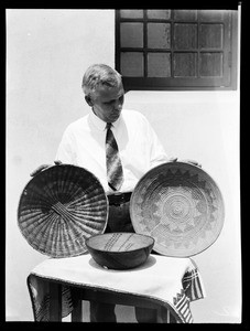 Man near three Native American woven baskets at the Pacific Southwest Museum