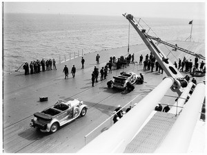 Mechanics adjusting the tires on an automobile on the deck of a battleship