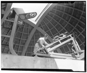 Scientist checking a telescope element beneath the Griffith Park Observatory dome, ca.1930-1950