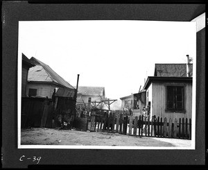 Unidentified shacks behind a makeshift picket fence