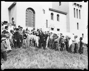 Few dozen boys huddled around a man about to throw an object