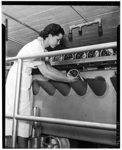 Woman loading cans of lemon juice in an unidentified factory