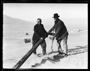 Two men digging a hole for a cross at a funeral in the desert