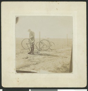 Cyclist fixing a tire, ca.1890
