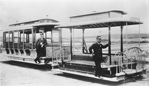 Open-air streetcar with its trailer and two operators on west Seventh Street looking north from Alvarado Street, ca.1890