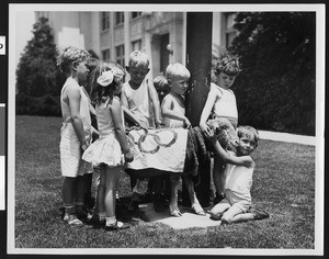 Close-up view of eight children surrounding a sheep, 1932