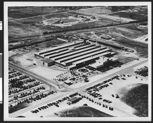 Exterior aerial view of a factory, showing a railroad track in the background, ca.1940