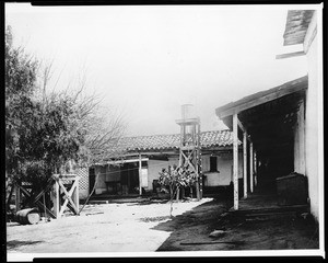 View of the corridor along the dining room at the Gaujome Ranch showing a water tower, 1870-1880