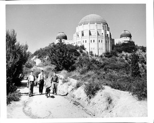 Exterior view of the Griffith Park Observatory showing three teenage boys hiking on a trail nearby, 1930-1950