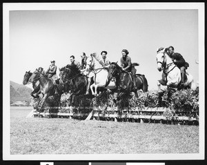 A group of equitation riders making a jump simultaneously, ca.1930