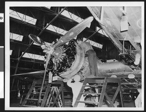 Men attending to a large propeller on an aircraft assembly line, ca.1940