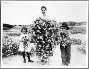 Ruth Barker with niece and nephew holding desert wild flowers, between Indian Wells and Indio, California, 1920