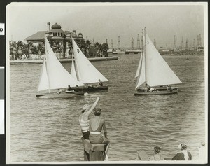 Sailboats on the ocean, showing two women in the extreme foreground, ca.1930