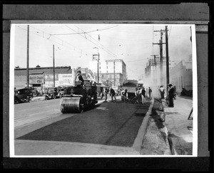 View of a commercial street being repaved, showing workmen and equipment