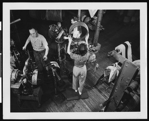 Three factory workers making beads (treads?) and working with machinery, ca.1945