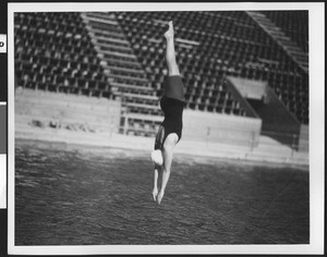 Woman diver plunging into the swimming pool water, ca.1930