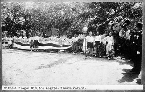 Men standing near the Chinese Dragon costume at the Old Los Angeles Fiesta Parade