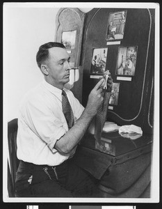 Man holding a metal stereotype head showing the offset for reversing the plate, ca.1932