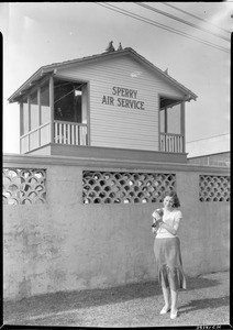 Woman standing in front of a Sperry Air Service pigeon coop in Los Angeles