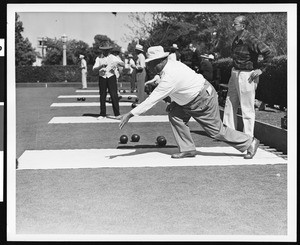 A close-up view of a man delivering a bowl during a lawn bowling game, ca.1930